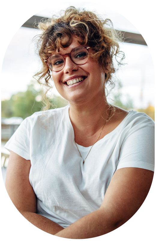 woman with curly hair and glasses smiling